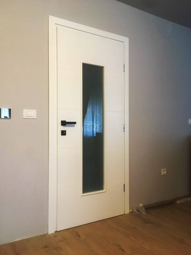 Bijela sobna vrata sa staklom, crtama i crnom kvakom